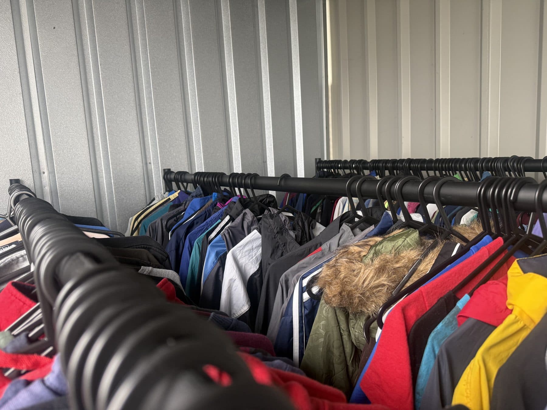 A long rail of vintage jackets and coats in the unit, including a fur-trimmed parka and red, yellow and blue outerwear.